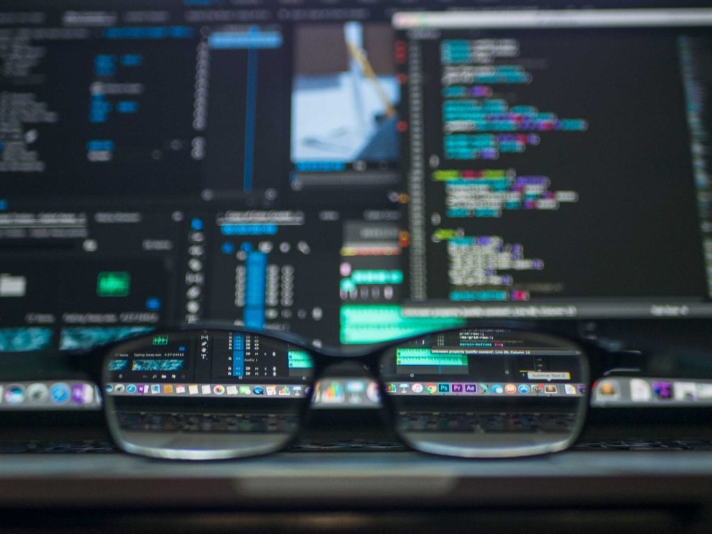 Image of glasses in front of computer monitors