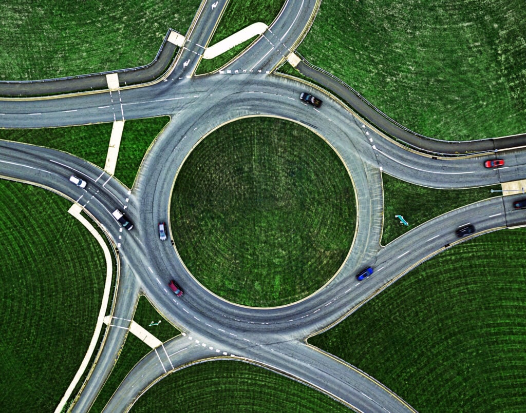 bird's eye view of highway roundabout with scattered cars on the road