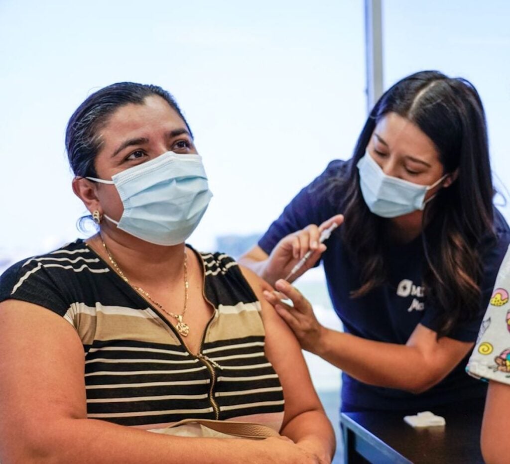 Photo of a woman getting vaccinated with girl looking on