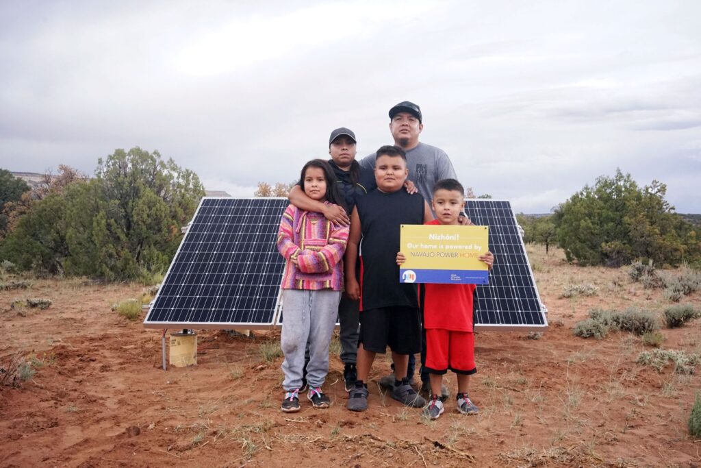 Image of people in front of solar panell holding "Navajo Power Home" sign. Source: Navajo Power Home